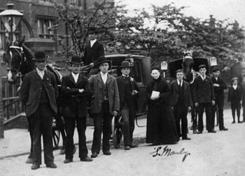 Group on the street in front of horse drawn carriages.